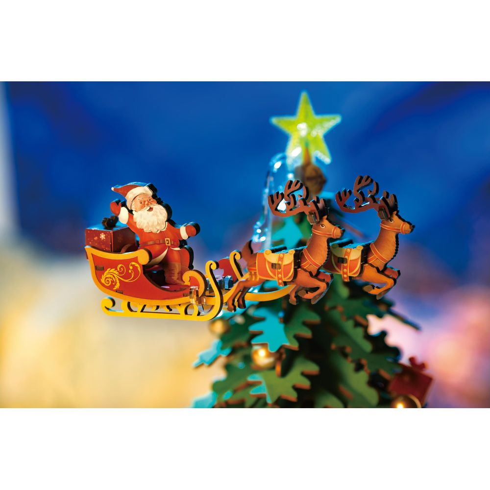 Ein hölzerner Weihnachtsmann in einem Schlitten, gezogen von Rentieren, fliegt vor einem Weihnachtsbaum.