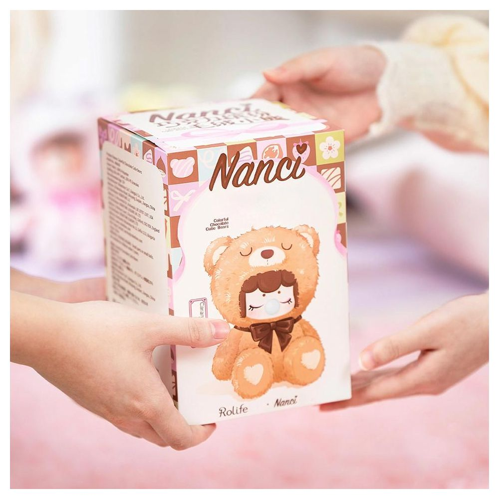 Deux mains tiennent une boîte Nanci avec un design d'ours en peluche.