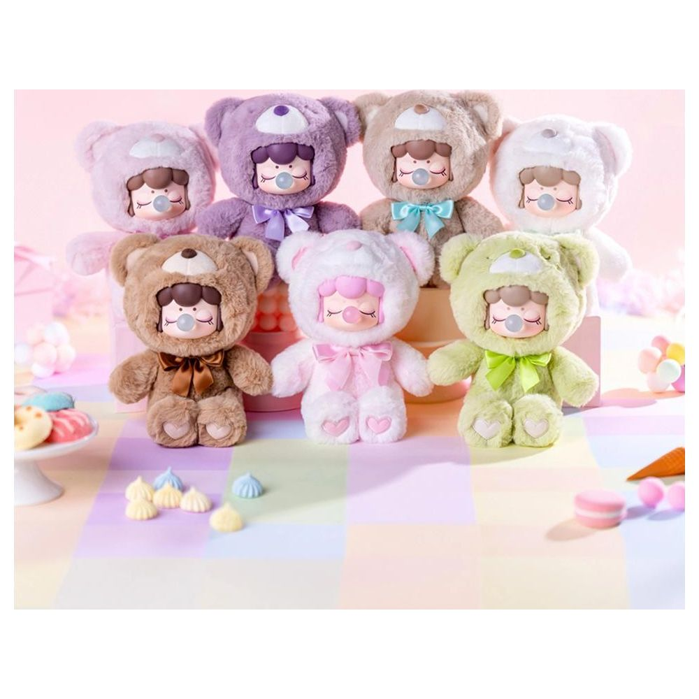 Sept figurines d'ours en peluche pastel avec tétines et nœuds sur une surface à carreaux.