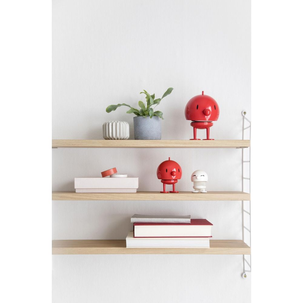 Due scaffali con decorazioni: figure rosse, pianta in vaso, scatole e libri.