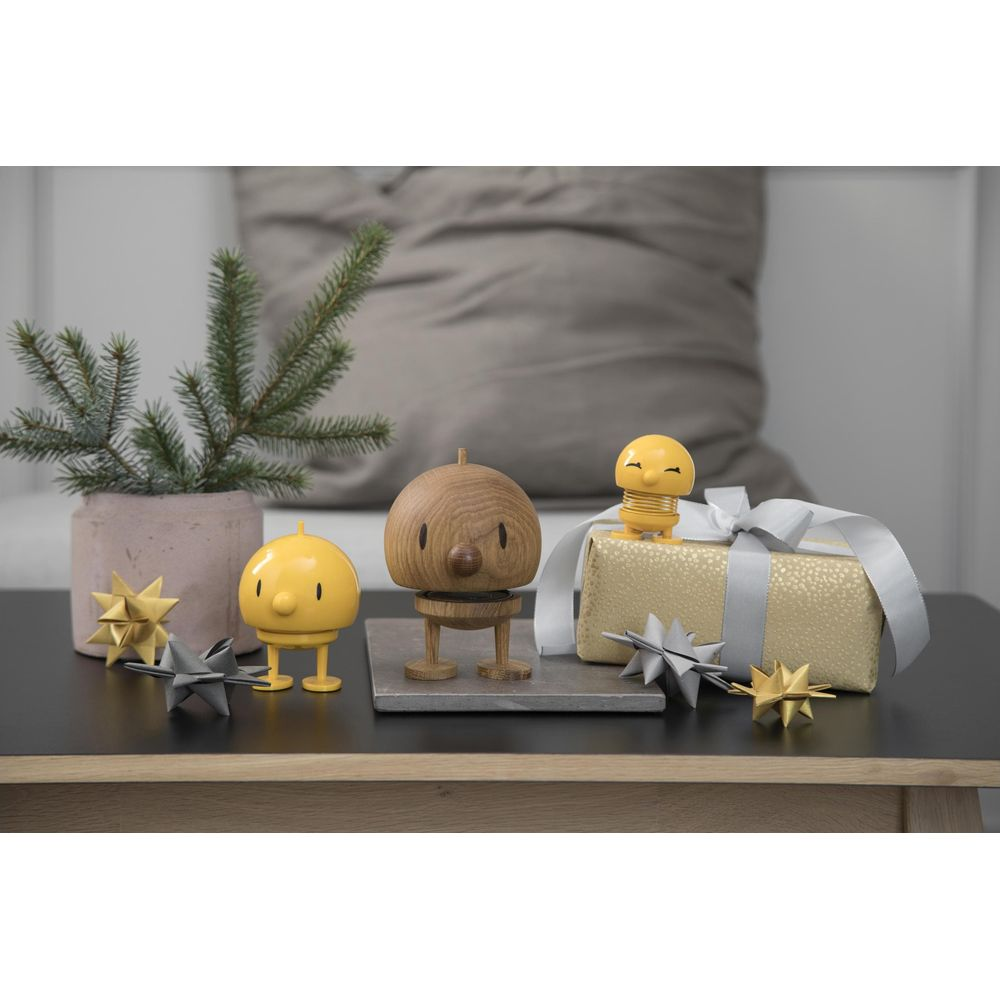 Figure in legno con personaggi gialli e un regalo su un tavolo.
