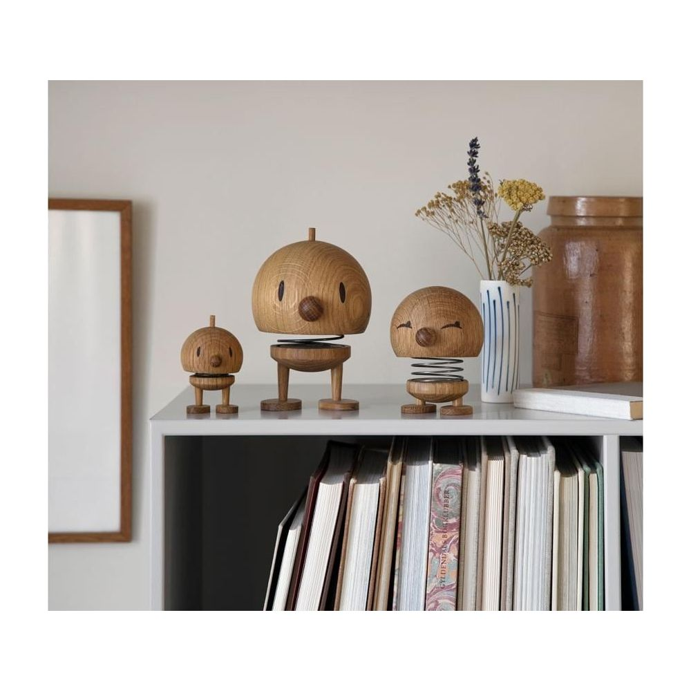 Tre figure in legno con molle su una libreria.