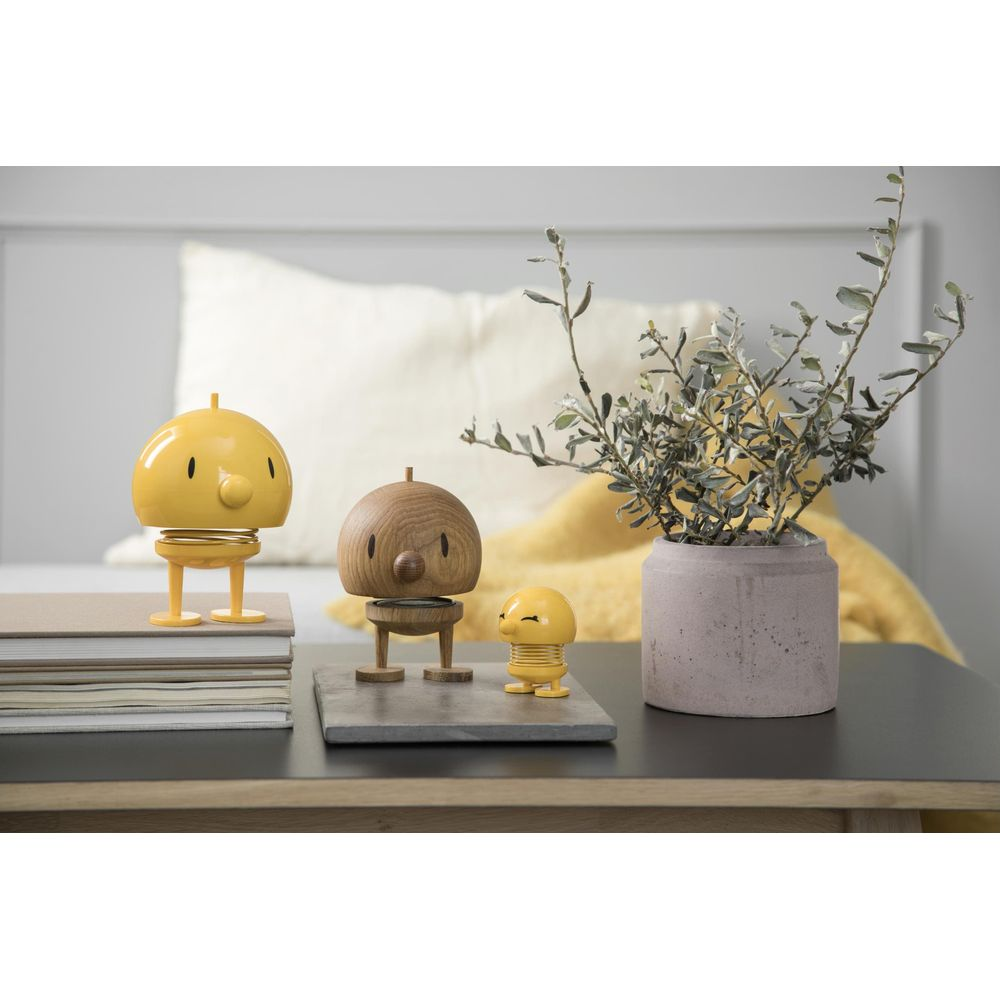Tre figure decorative: due gialle e una in legno, su un tavolo.