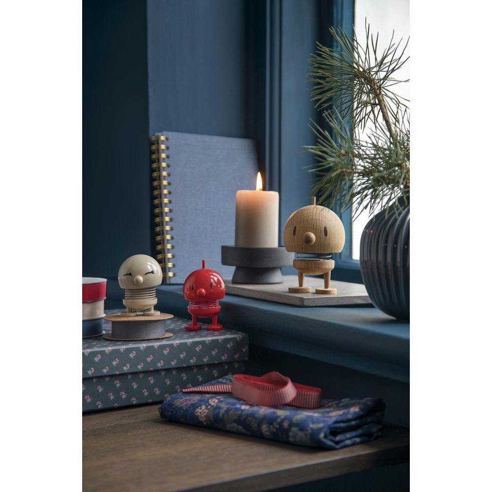 Davanzale accogliente con figure decorative, candela accesa e rami di pino.