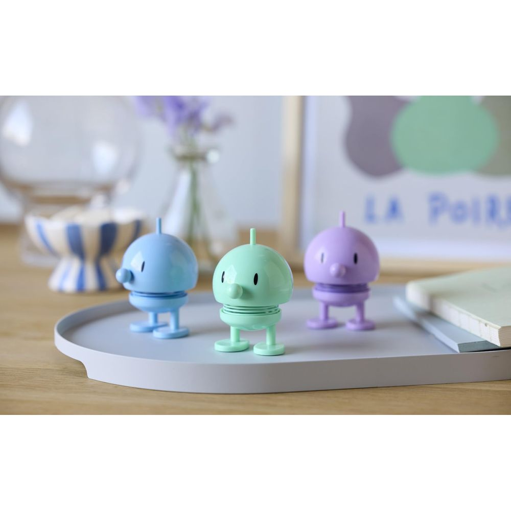 Tre statuette colorate su un vassoio. Blu, verde e viola.
