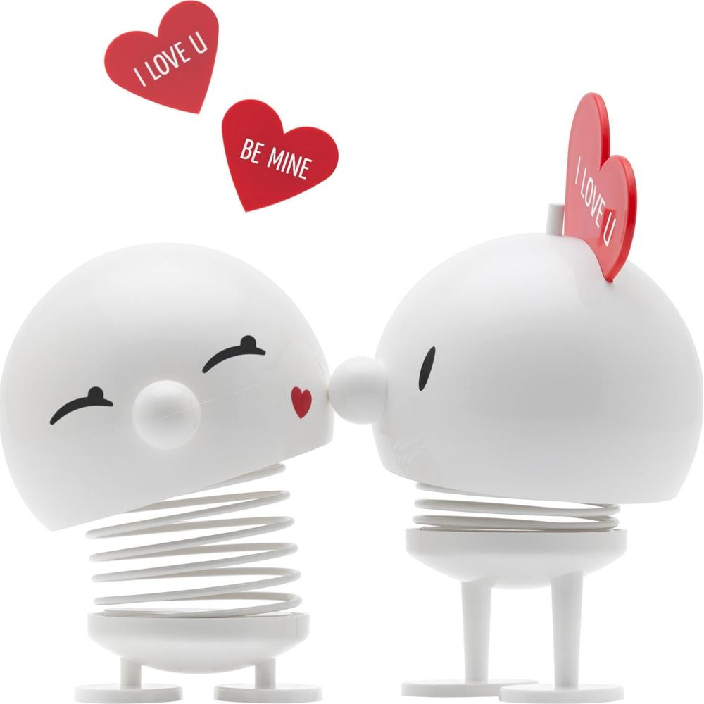 Due figure bianche a molla che si baciano, con cuori.