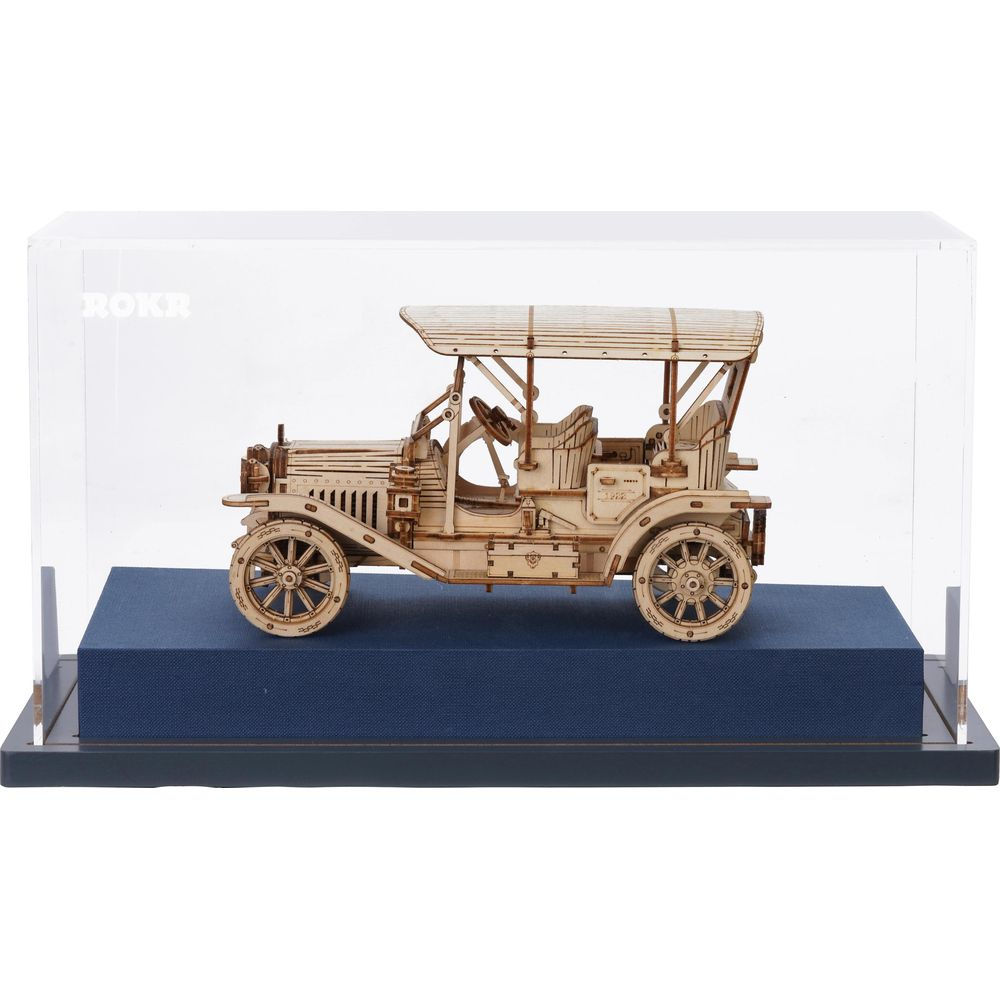 Ein hölzernes Modellauto im Vintage-Stil steht auf einem blauen Sockel unter einer Glasvitrine.