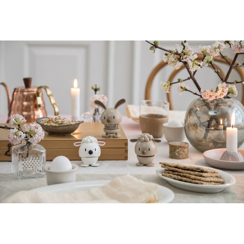 Tavola di Pasqua con portauova, teiera, fiori e candele accese.