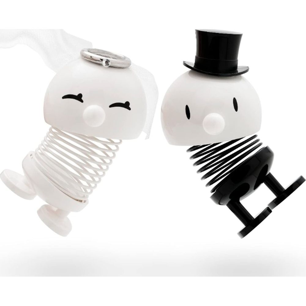 Zwei weiße und schwarze wackelnde Figuren mit Federn, Braut und Bräutigam.