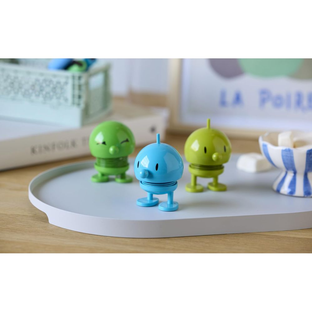 Tre piccole figure su un vassoio: due verdi e una blu.