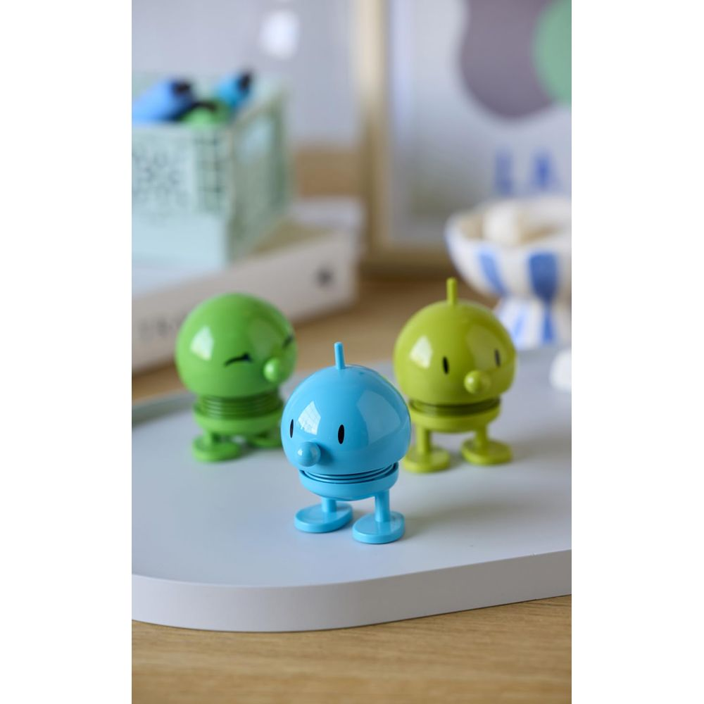 Tre simpatiche figure giocattolo su un vassoio, una blu e due verdi.