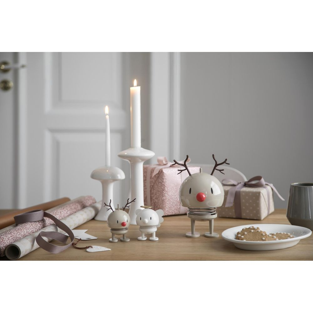 Decorazioni natalizie con candele, regali e figure di renne su un tavolo di legno.