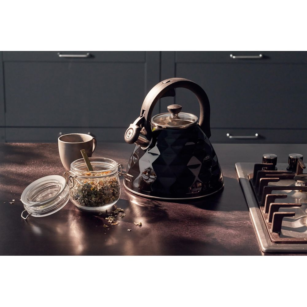 Schwarzer Teekessel, Teeglas und Gewürzglas auf dunkler Arbeitsplatte.