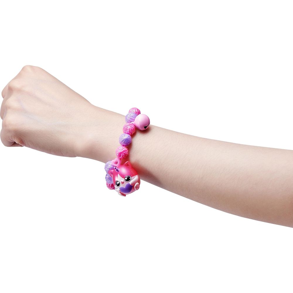 Ein pinkes Einhorn-Charms-Armband mit Pompon-Perlen am Handgelenk.