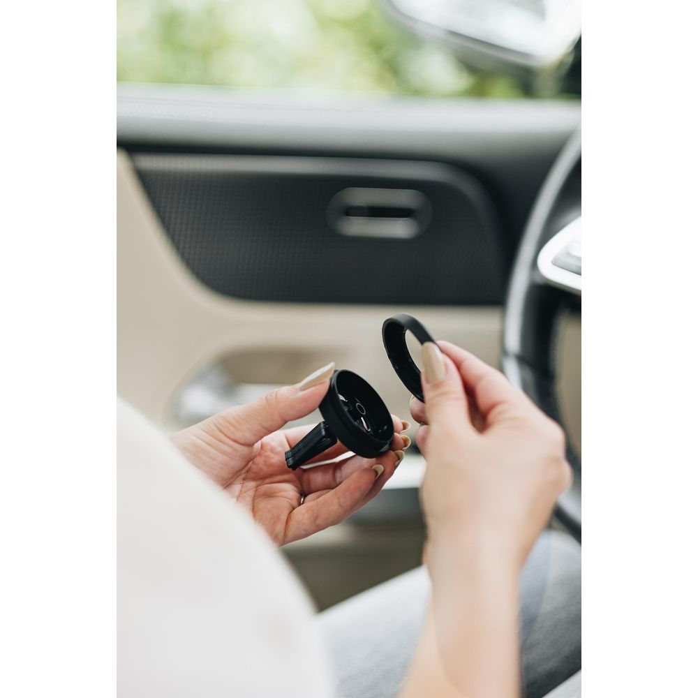 Person hält schwarzen Auto-Luftauslasshalter mit Ring im Auto.