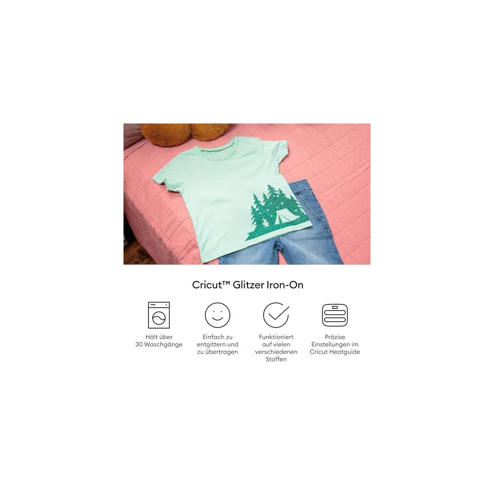 Hellgrünes T-Shirt mit Glitzer-Aufdruck von Bäumen und einem Zelt; daneben eine Jeans.