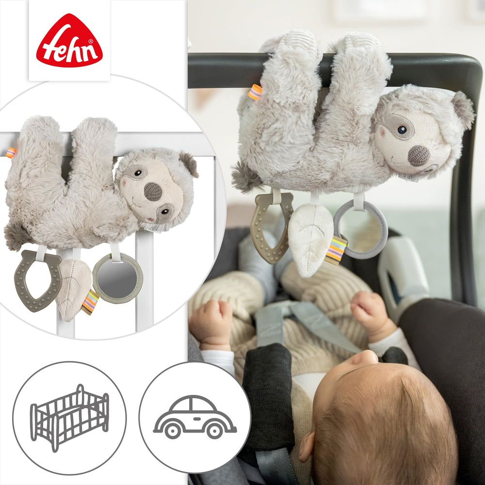 Ein Plüsch-Faultier-Spielzeug hängt an einem Kinderwagenbügel über einem Baby.