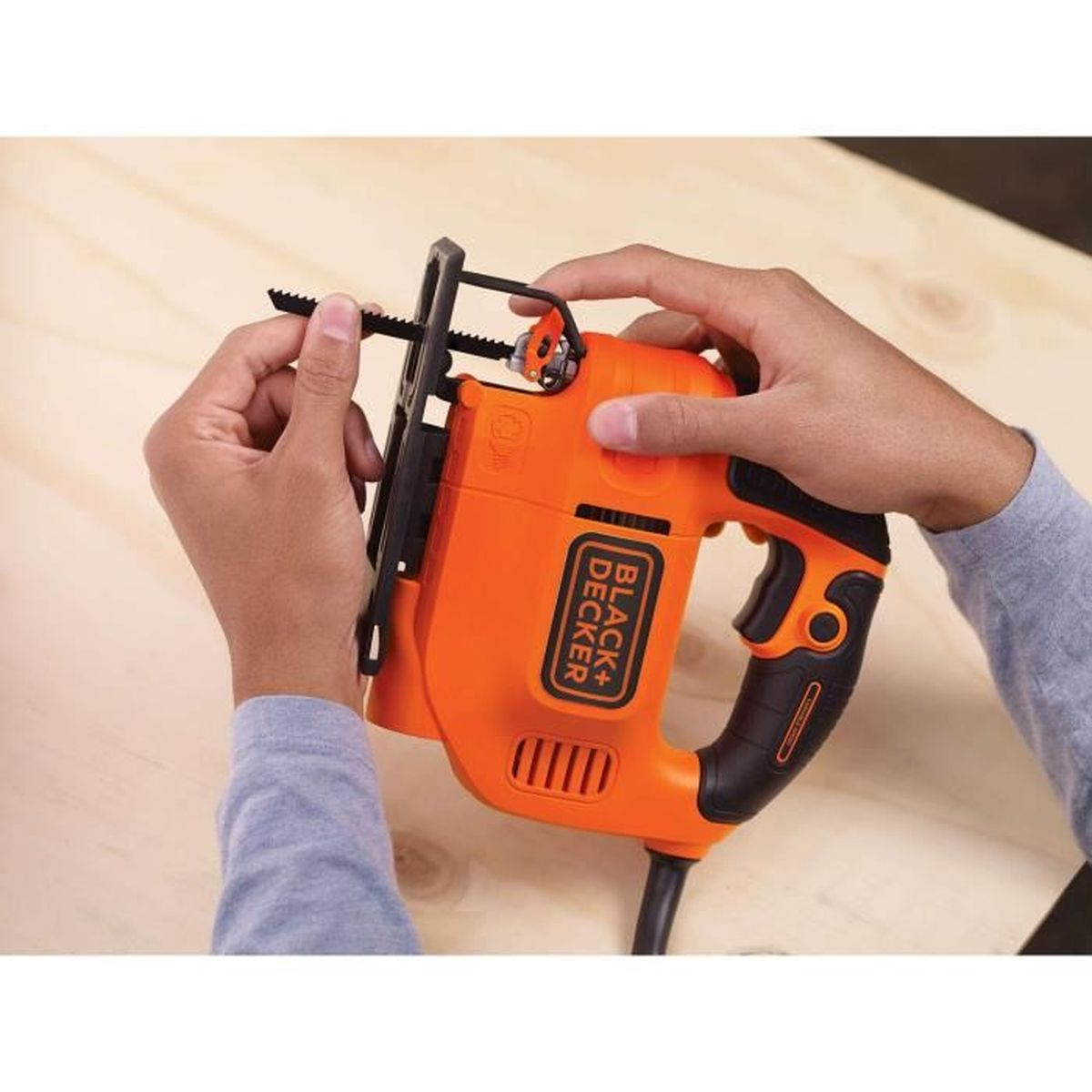 Handen stellen een oranje decoupeerzaag met Black+Decker logo in op hout.