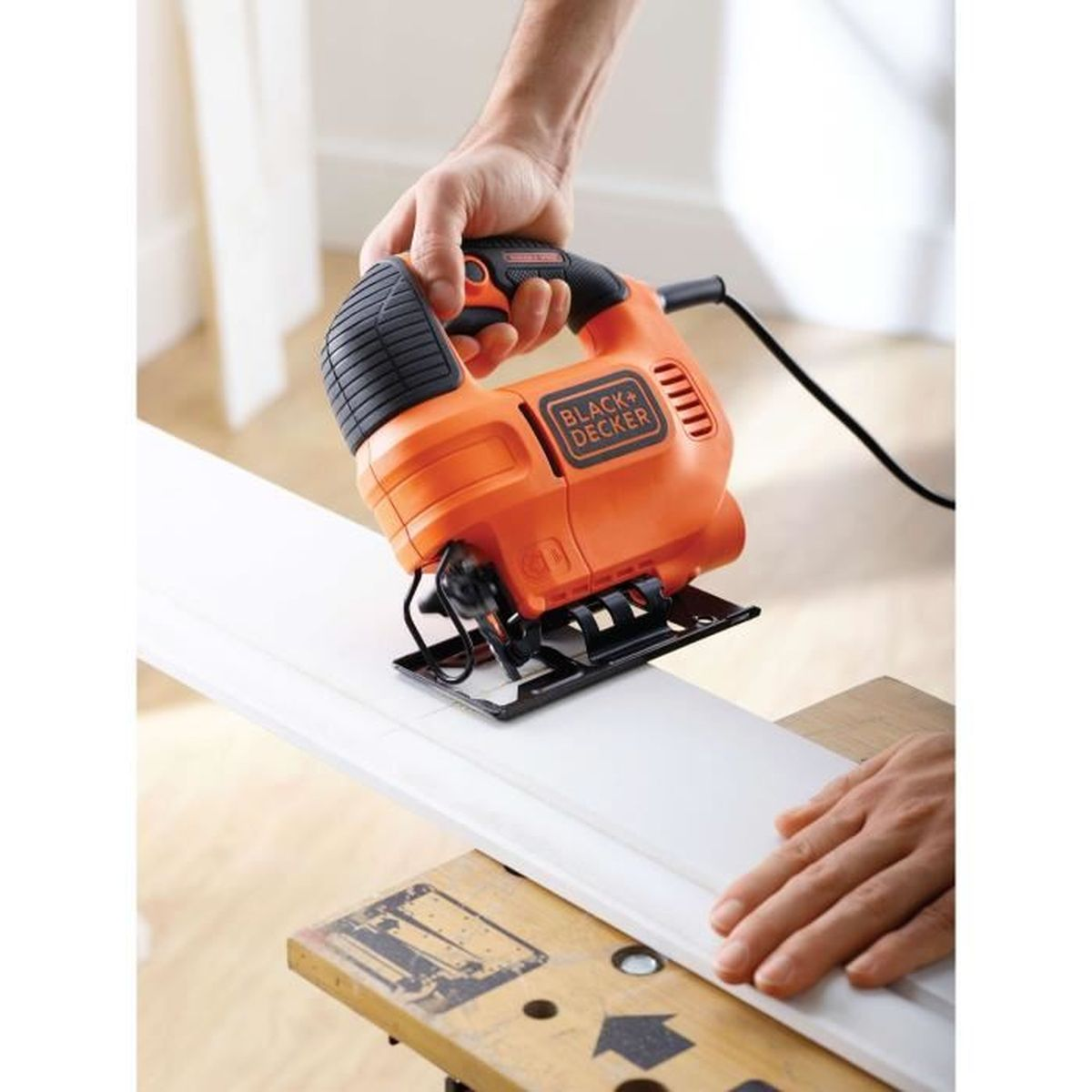 Een oranje decoupeerzaag van Black+Decker snijdt een wit stuk materiaal.