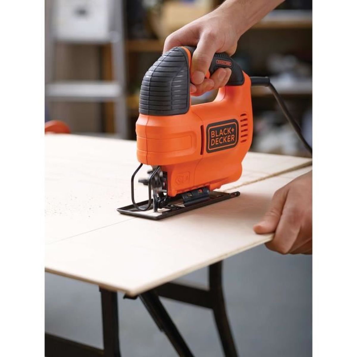 Een oranje Black+Decker decoupeerzaag wordt gebruikt om hout te snijden.