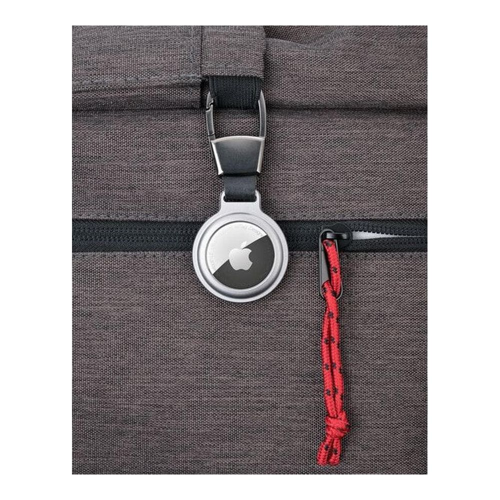Ein silberner Apple AirTag mit schwarzem Logo hängt an einem Rucksack. Daneben ein rotes Seil.