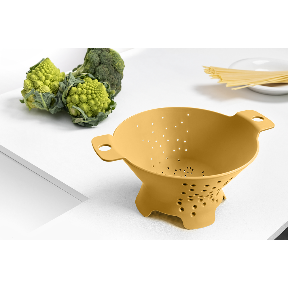 Ein gelber Sieb mit Romanesco und Brokkoli auf weißem Tisch.