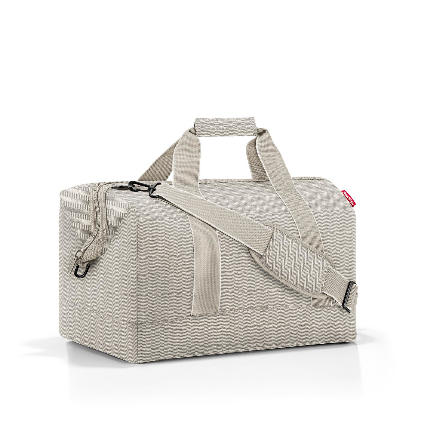 Eine beige Reisetasche mit Tragegriffen und einem Schultergurt auf weißem Hintergrund.