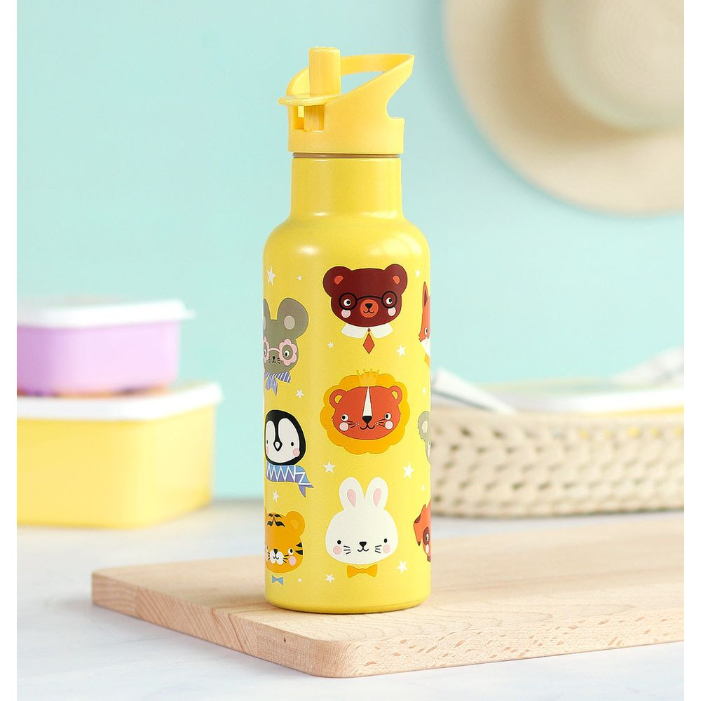 Eine gelbe Wasserflasche mit Tiergesichtern, auf einem Holzbrett.