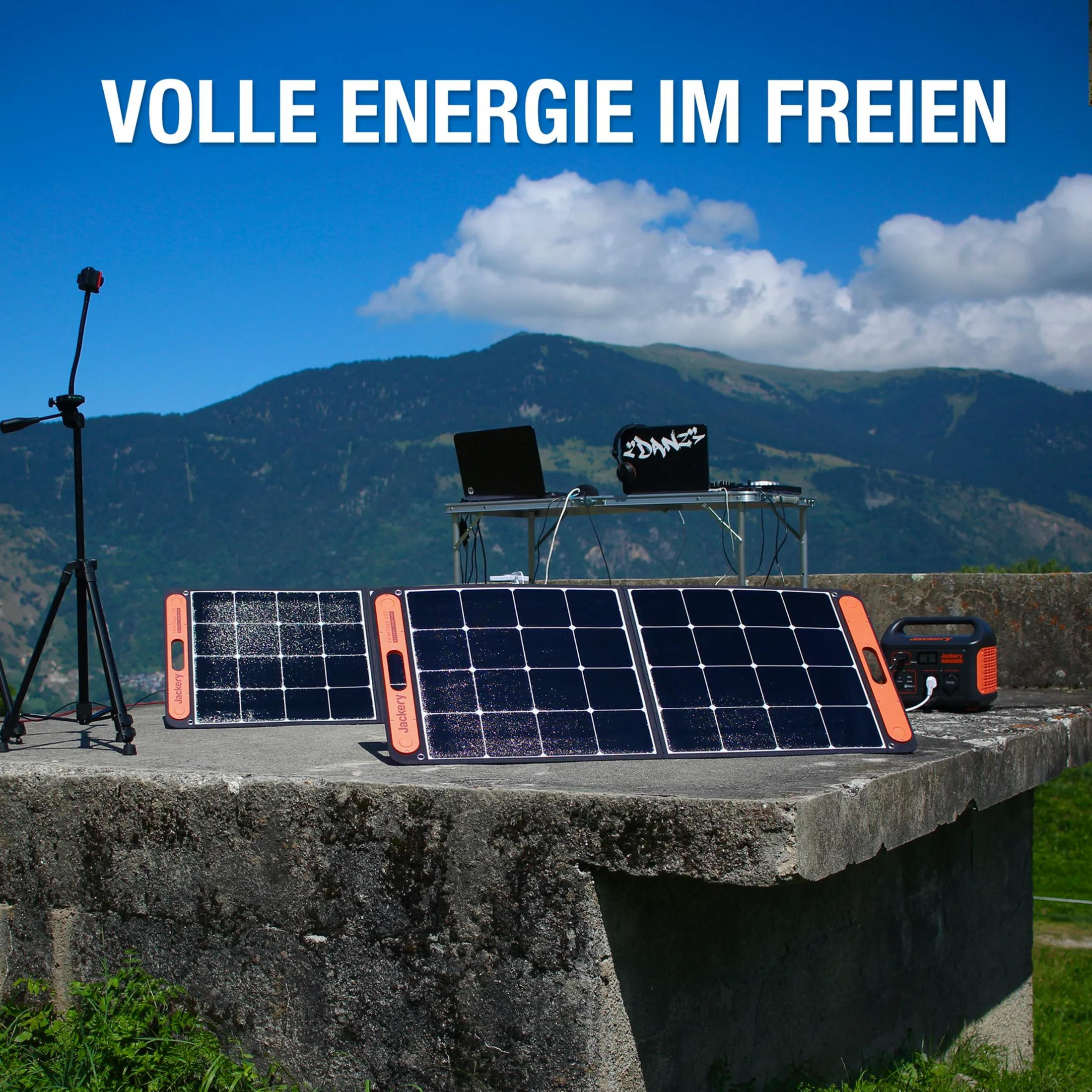 Zonnepanelen met een draagbaar aggregaat op een betonnen muur voor bergen.