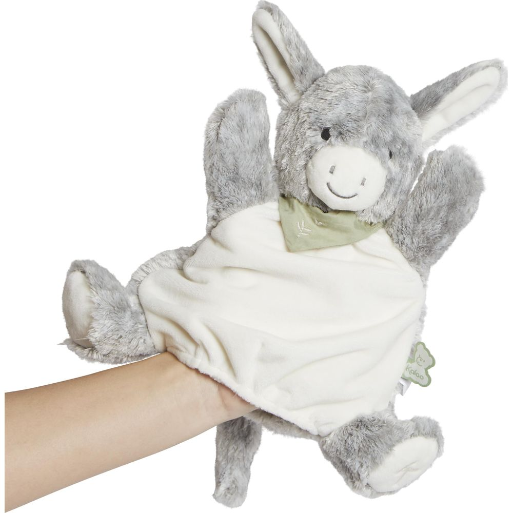 Eine graue Plüsch-Eselsfigur mit grünem Halstuch am Hals wird von einer Hand gehalten.