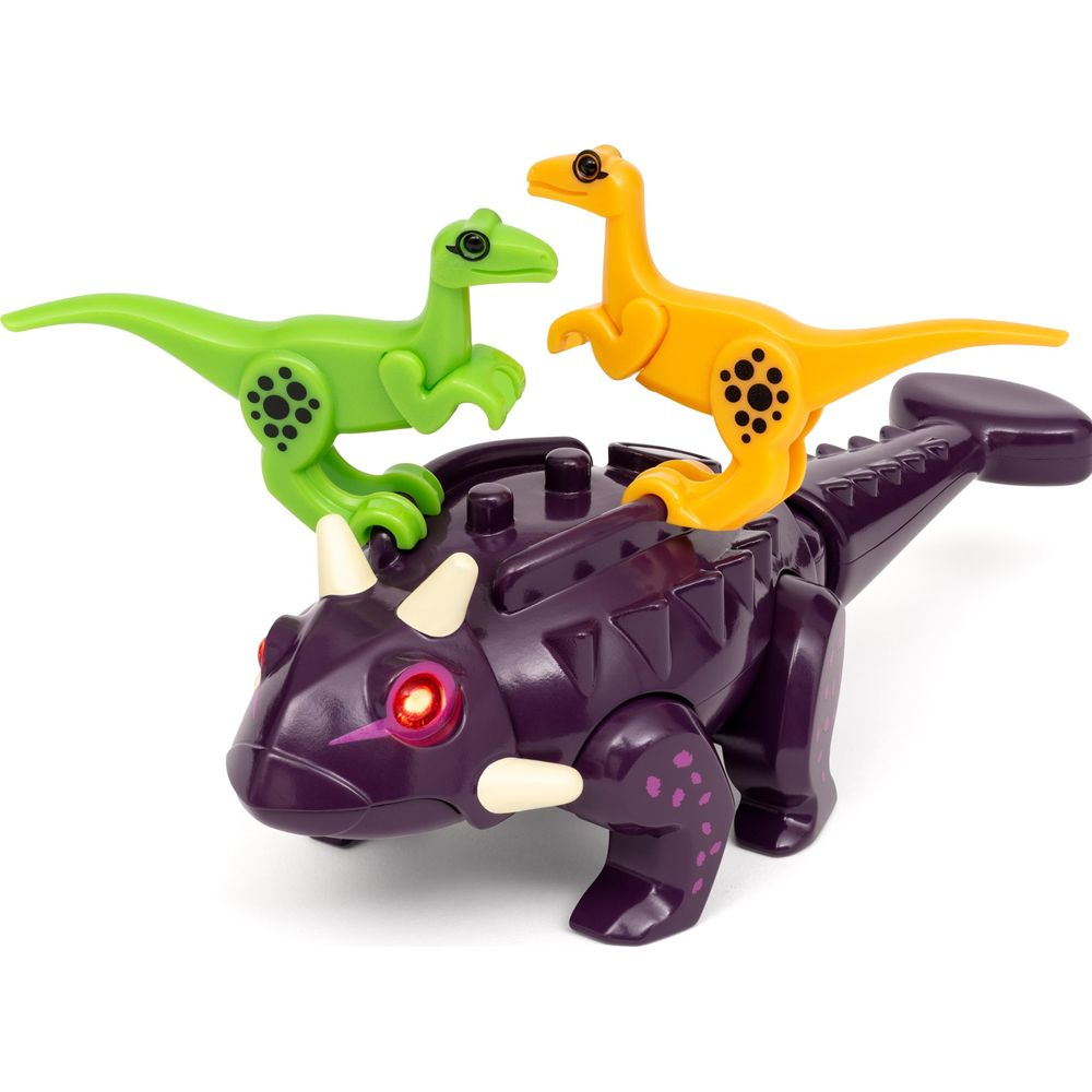 Drei Spielzeug-Dinosaurier: ein violetter Triceratops mit zwei kleineren grünen und gelben Raptoren.