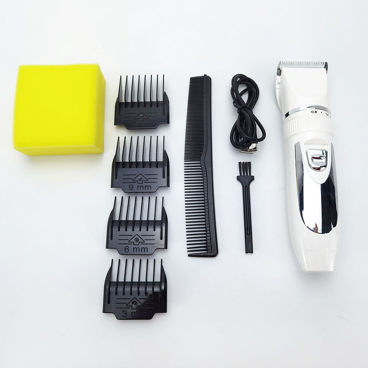 Ein weißer Haarschneider mit Zubehör: Bürste, Kamm, Ladekabel, gelber Schwamm, 4 Aufsätze.