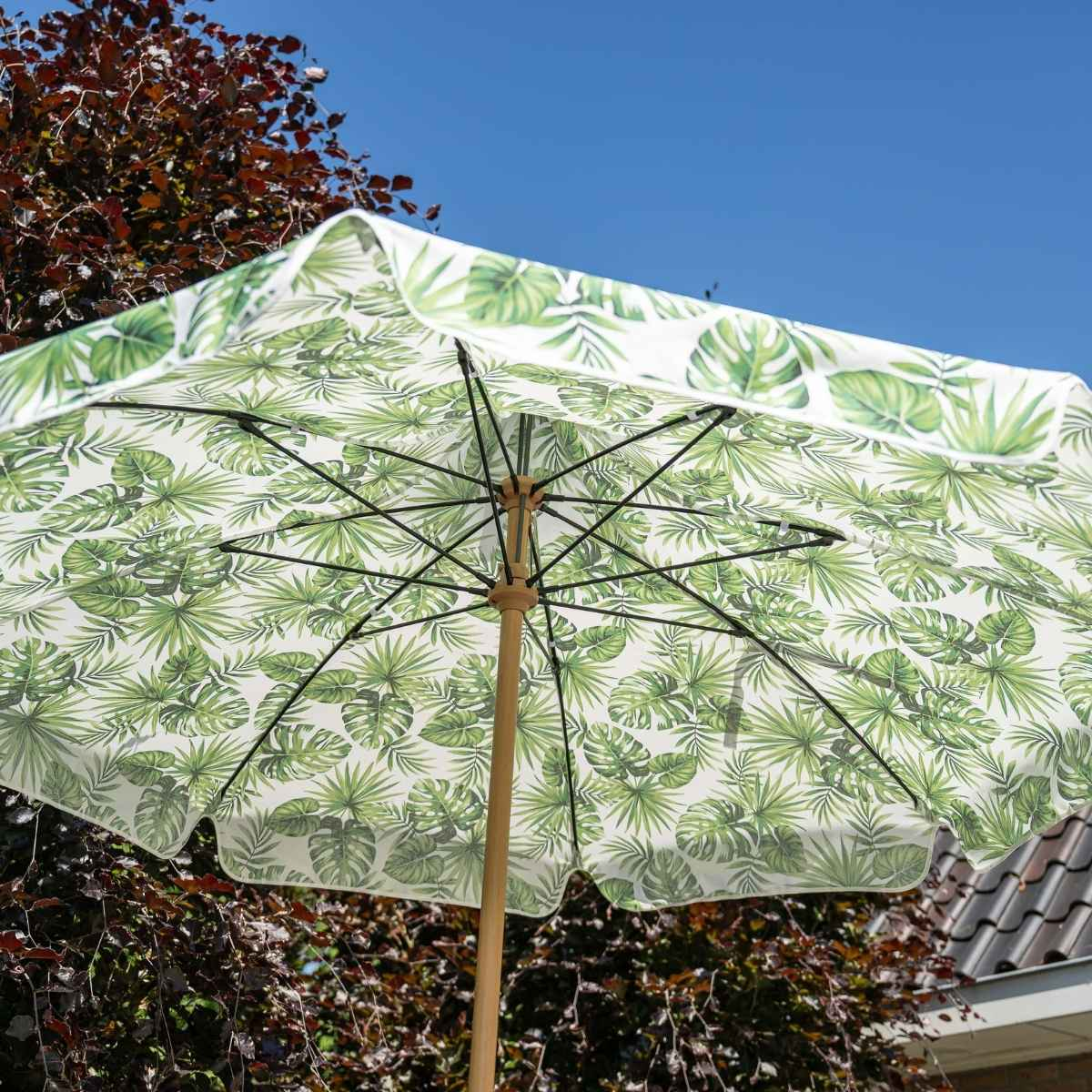 Een parasol met bladerpatroon tegen een blauwe lucht.