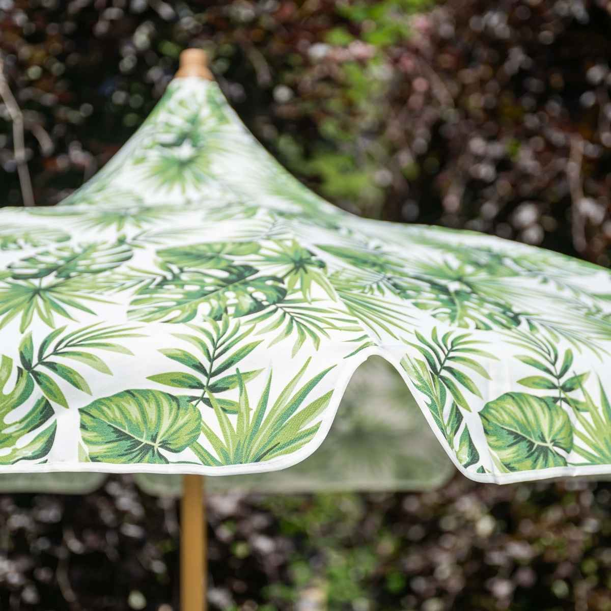 Een witte parasol met groen tropisch bladerpatroon.