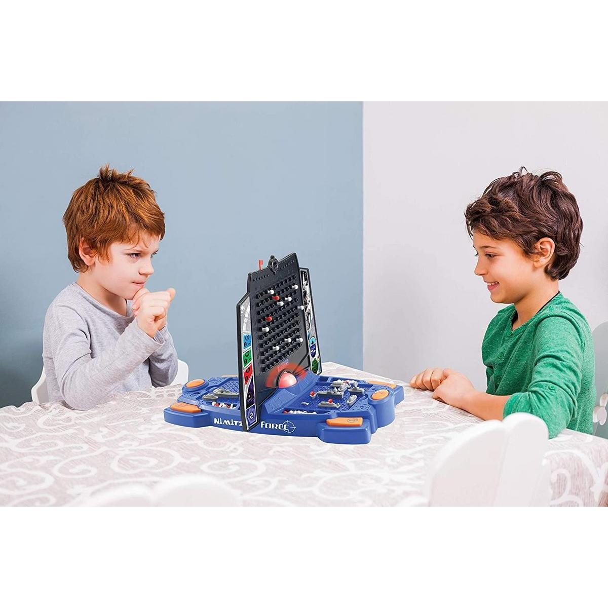 Dos niños jugando un juego de mesa de combate naval. Un niño se concentra, el otro sonríe.