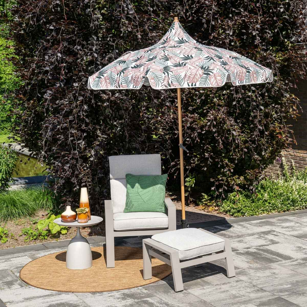 Tuinmeubelen: fauteuil, hocker, bijzettafel, parasol met bladerpatroon.