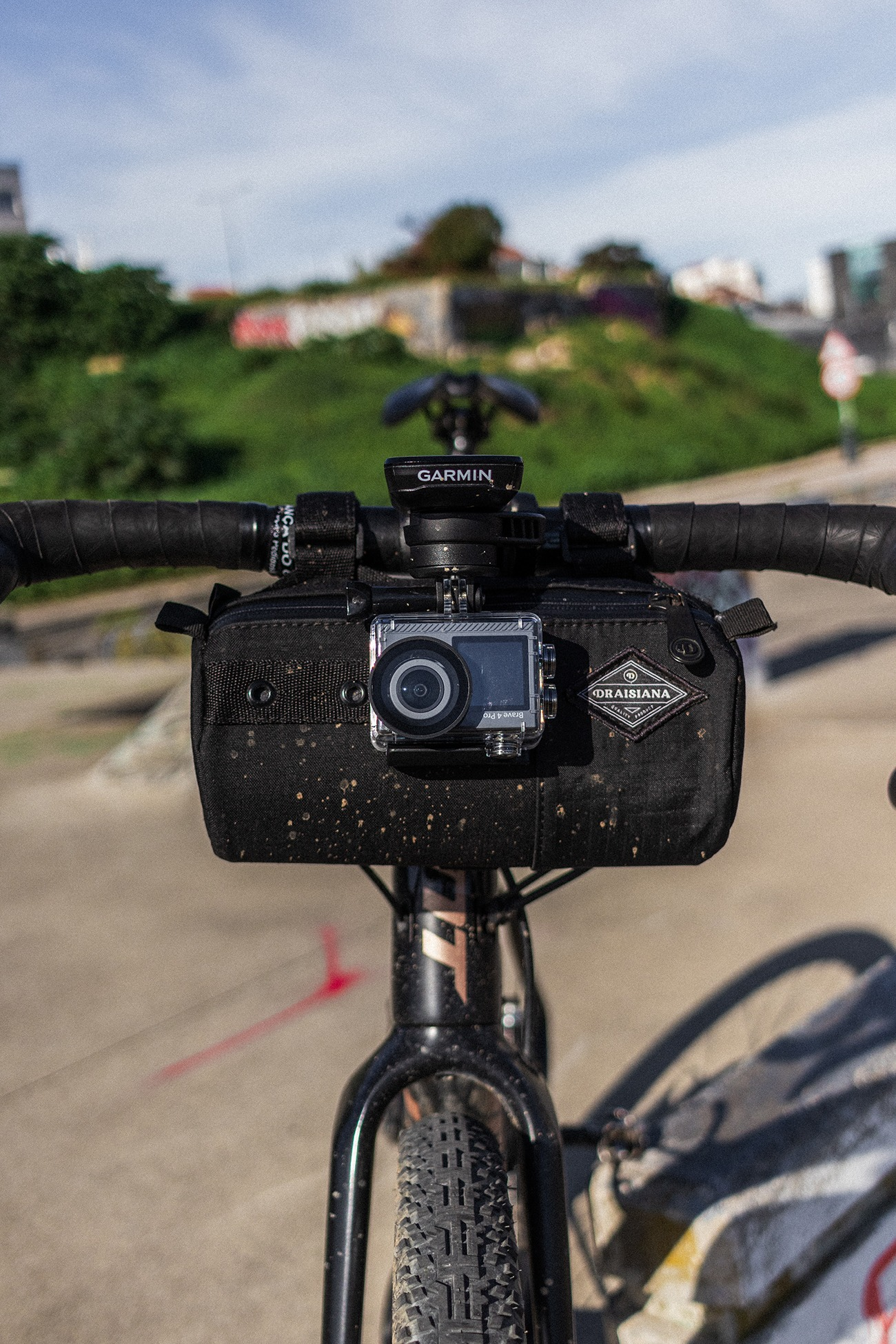 Fahrradlenker mit schwarzer Lenkertasche, Action-Kamera und Garmin-Gerät.