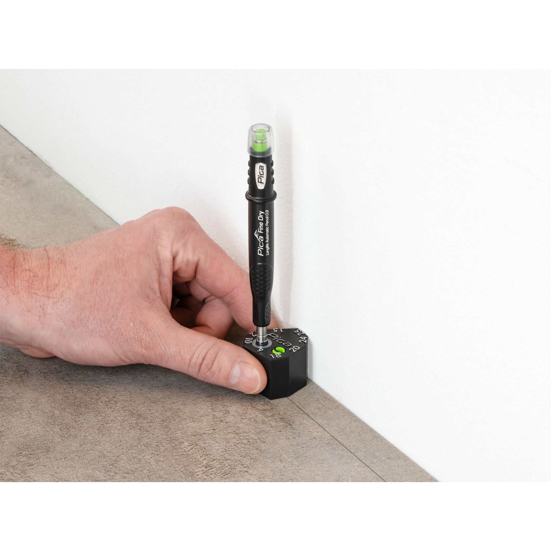 Ein Mann benutzt einen schwarzen Spezialstift mit einer Messvorrichtung auf dem Boden.