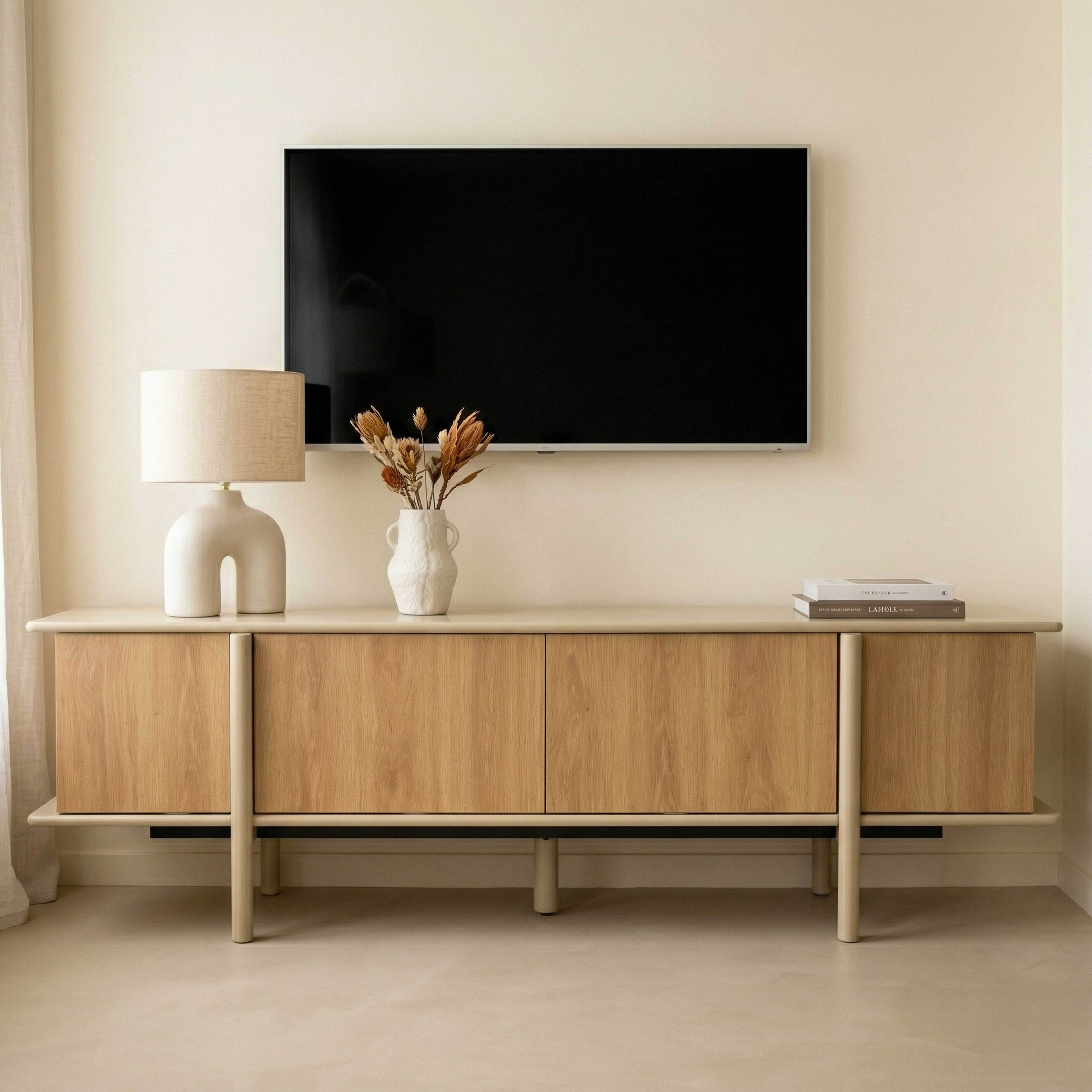 Ein TV-Schrank aus Holz mit einem Fernseher, einer Lampe und Trockenblumen.