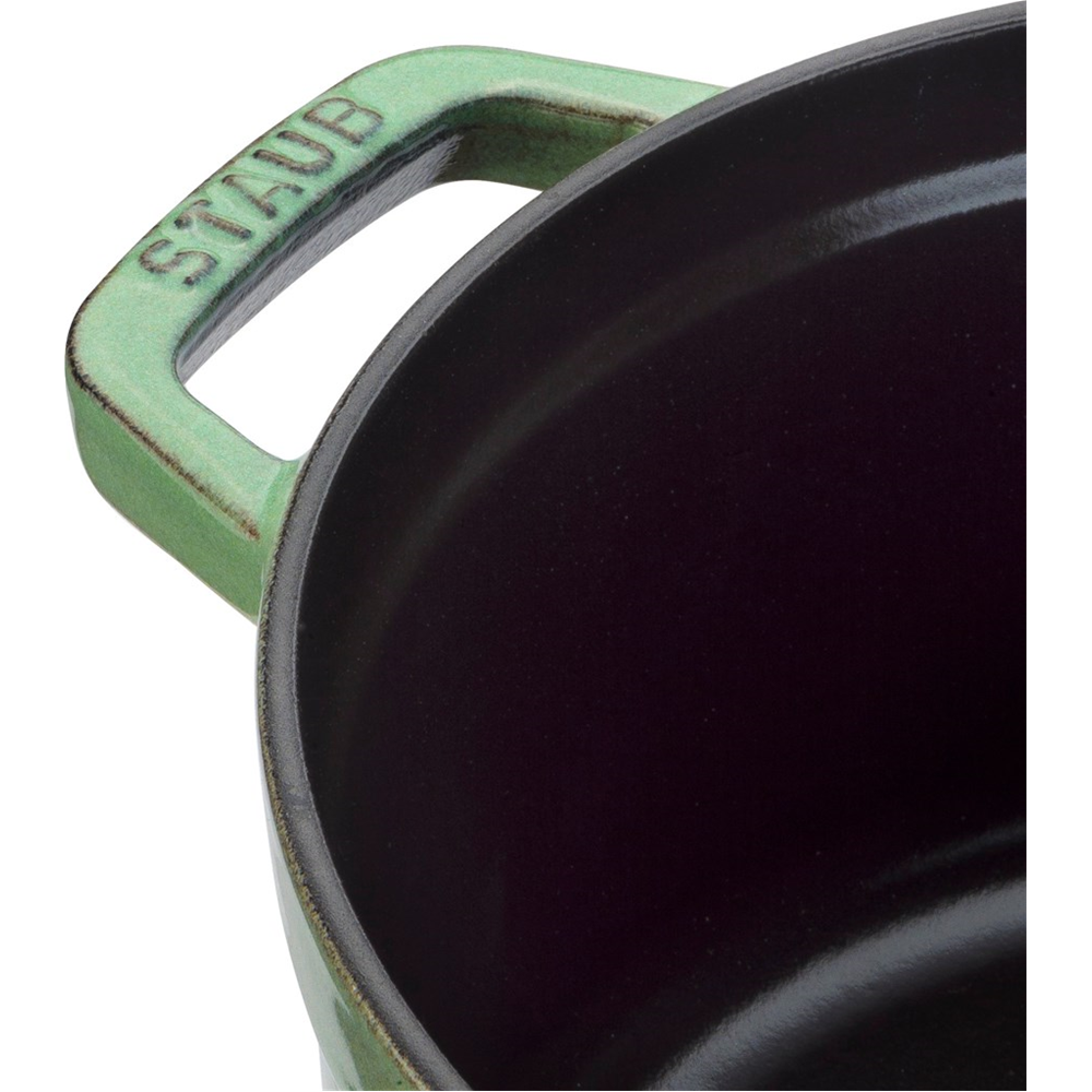 Grüner Kochtopfgriff mit der Aufschrift "STAUB" und schwarzer Innenseite.