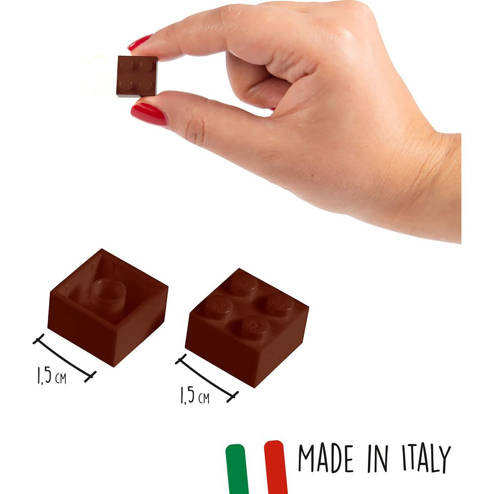 Una mano tiene un piccolo mattoncino marrone. Vicino ci sono altri due mattoncini da 1,5 cm.