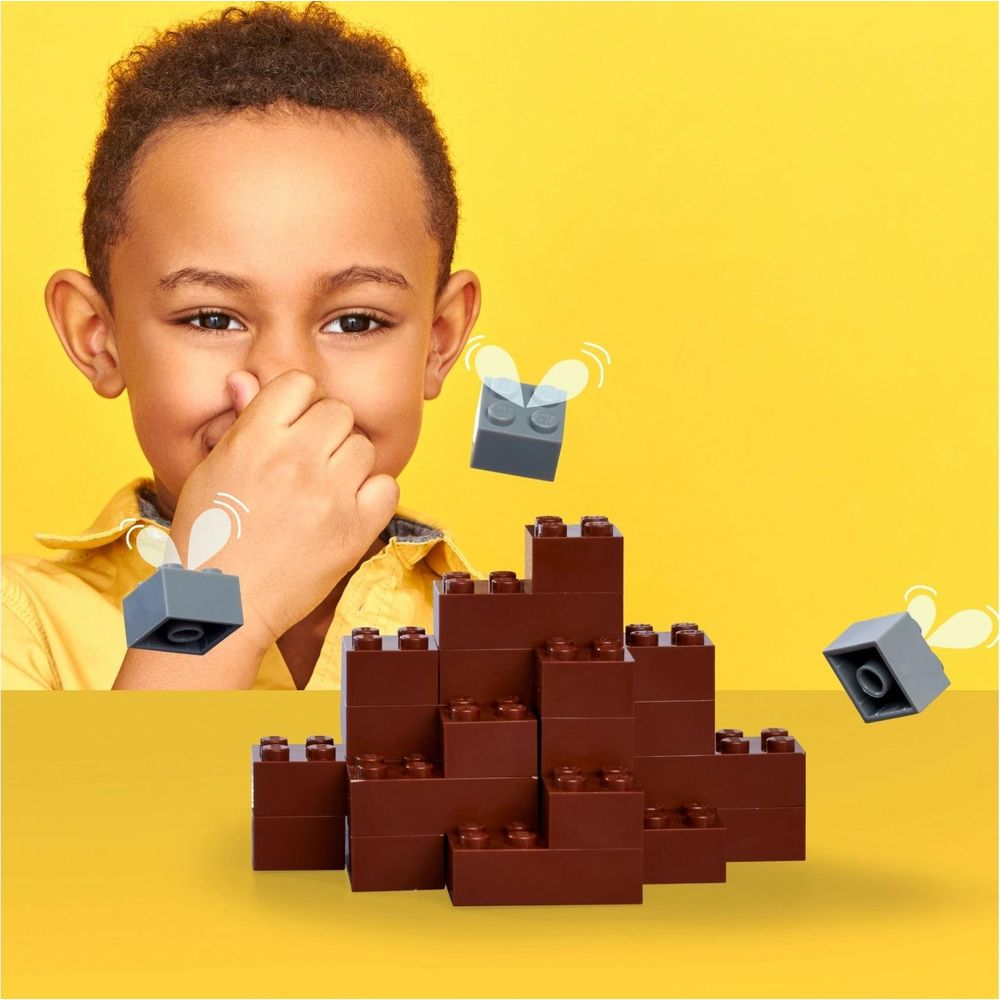 Un bambino si copre il naso da mattoncini Lego marroni e moscerini Lego grigi.