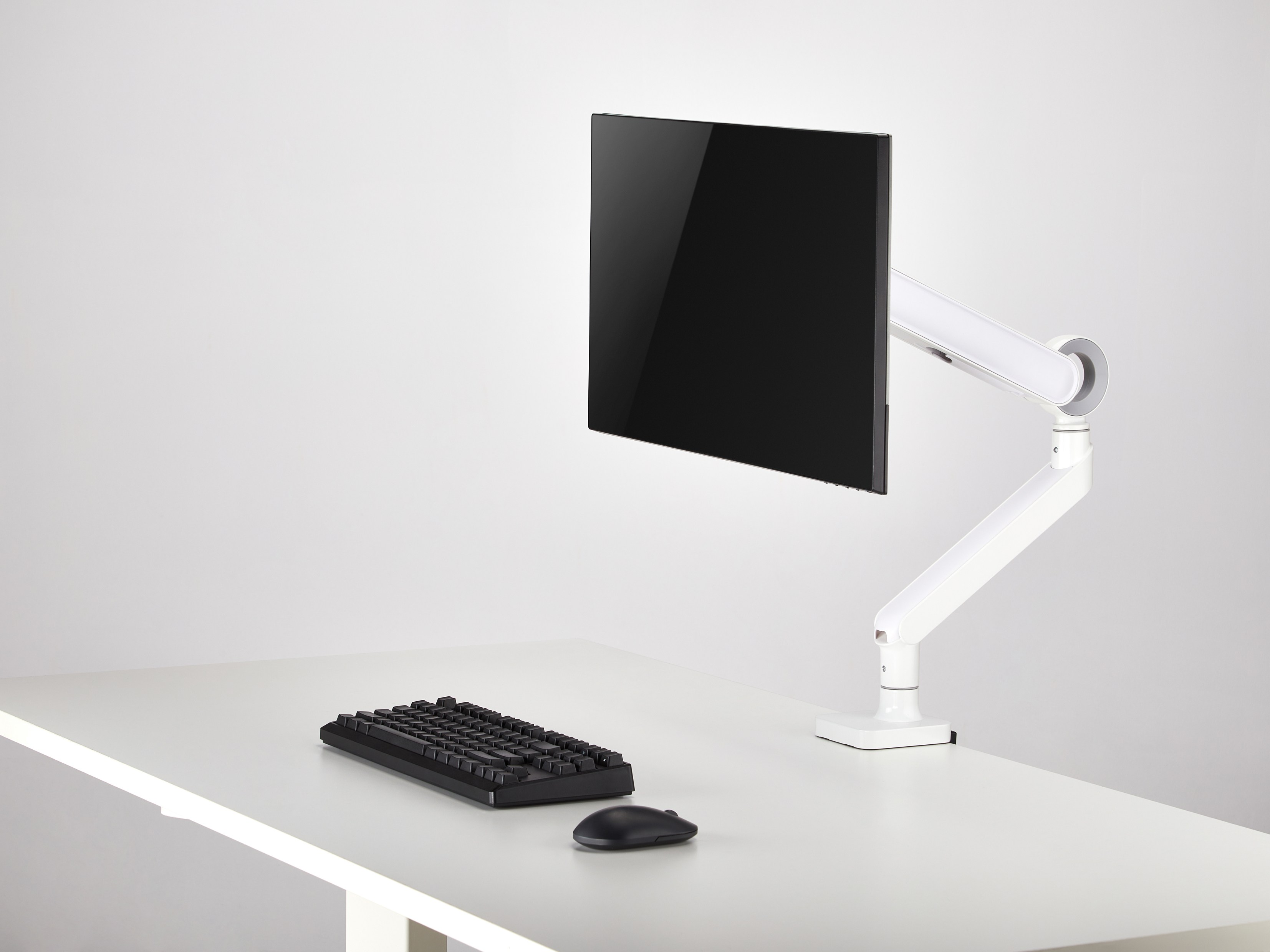 Ein schwarzes Keyboard und eine Maus stehen auf einem weißen Schreibtisch.