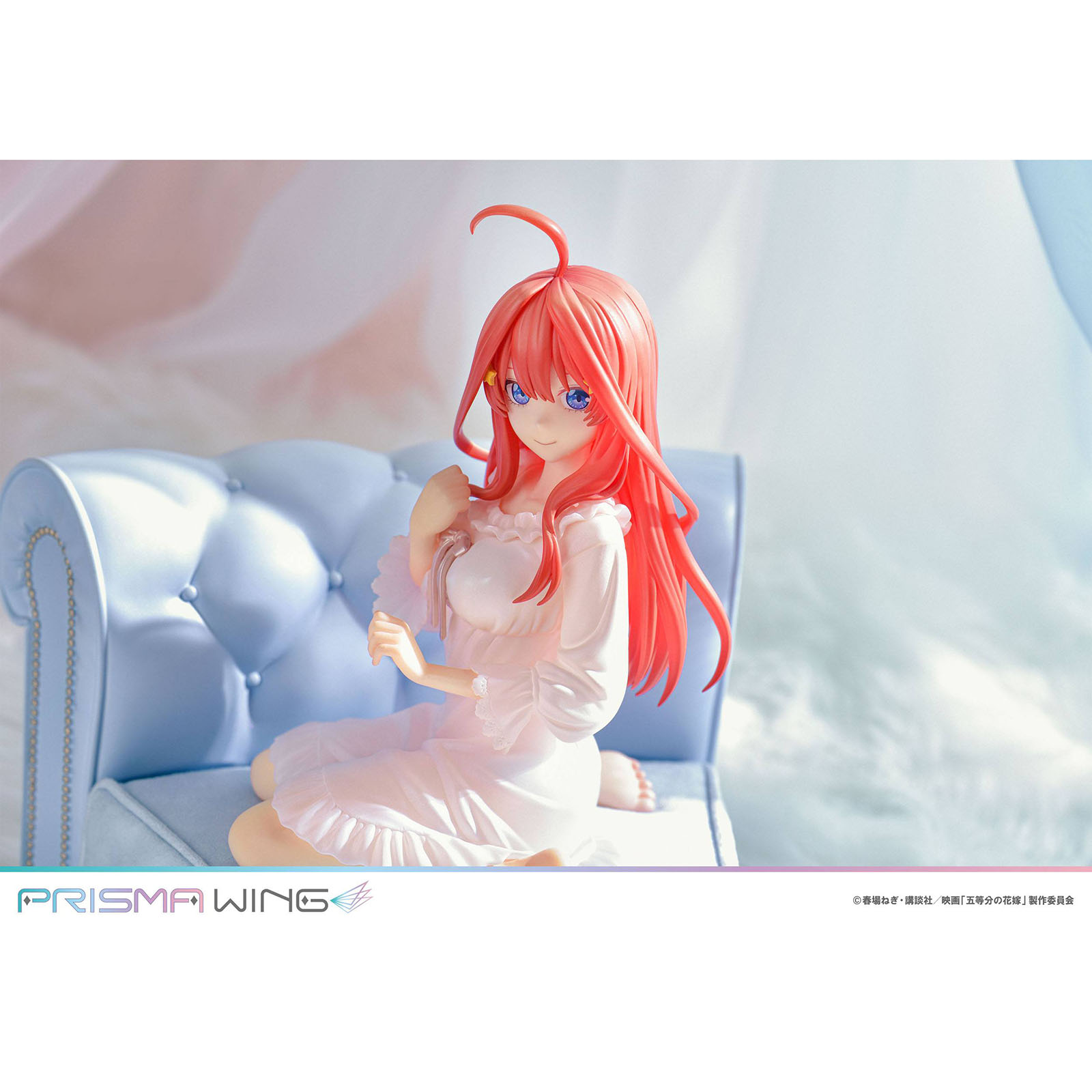 Eine Anime-Figur mit korallenroten Haaren sitzt auf einem hellblauen Sofa.