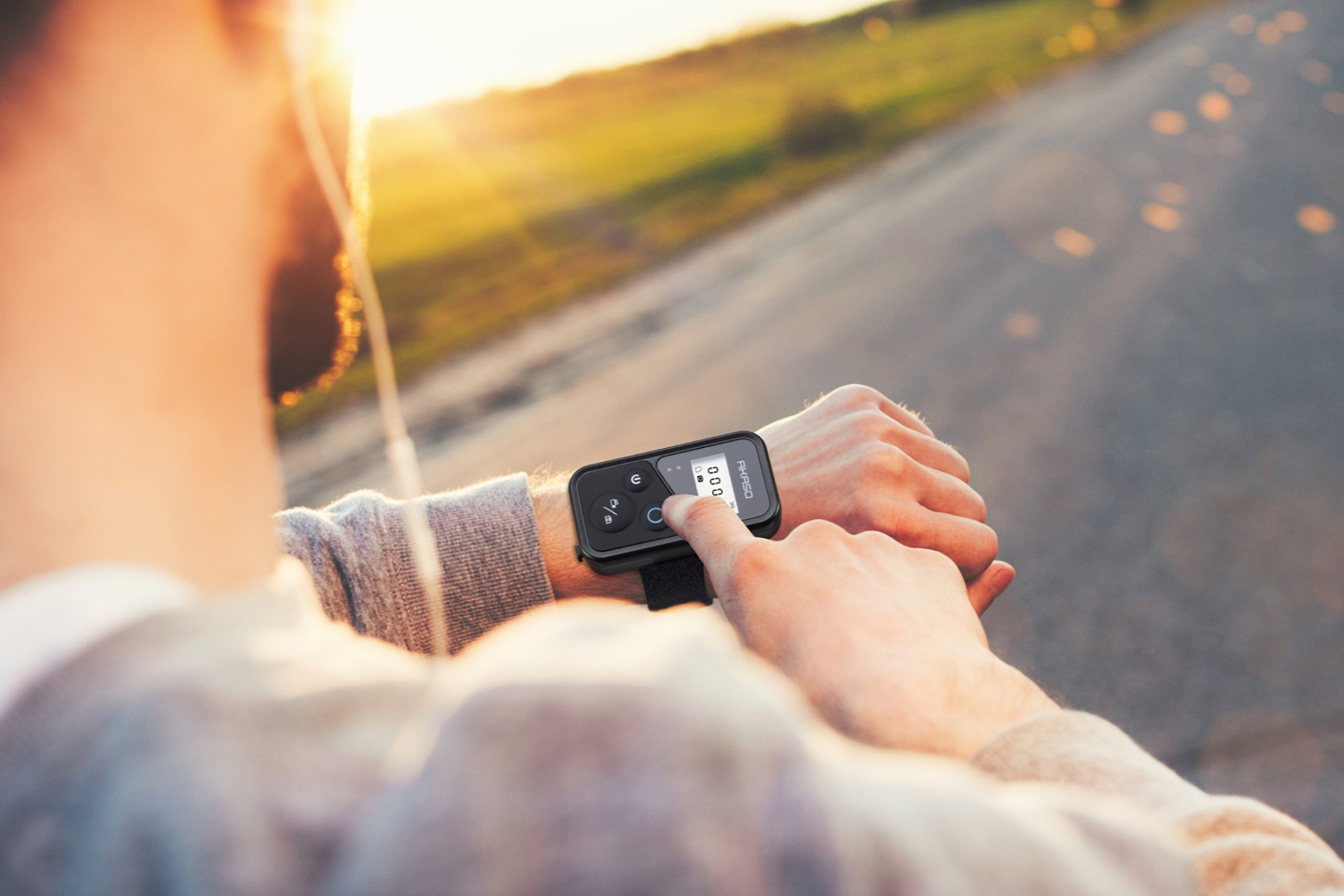 Eine Hand bedient eine Armbanduhr mit Touchscreen, im Sonnenuntergang, draußen.