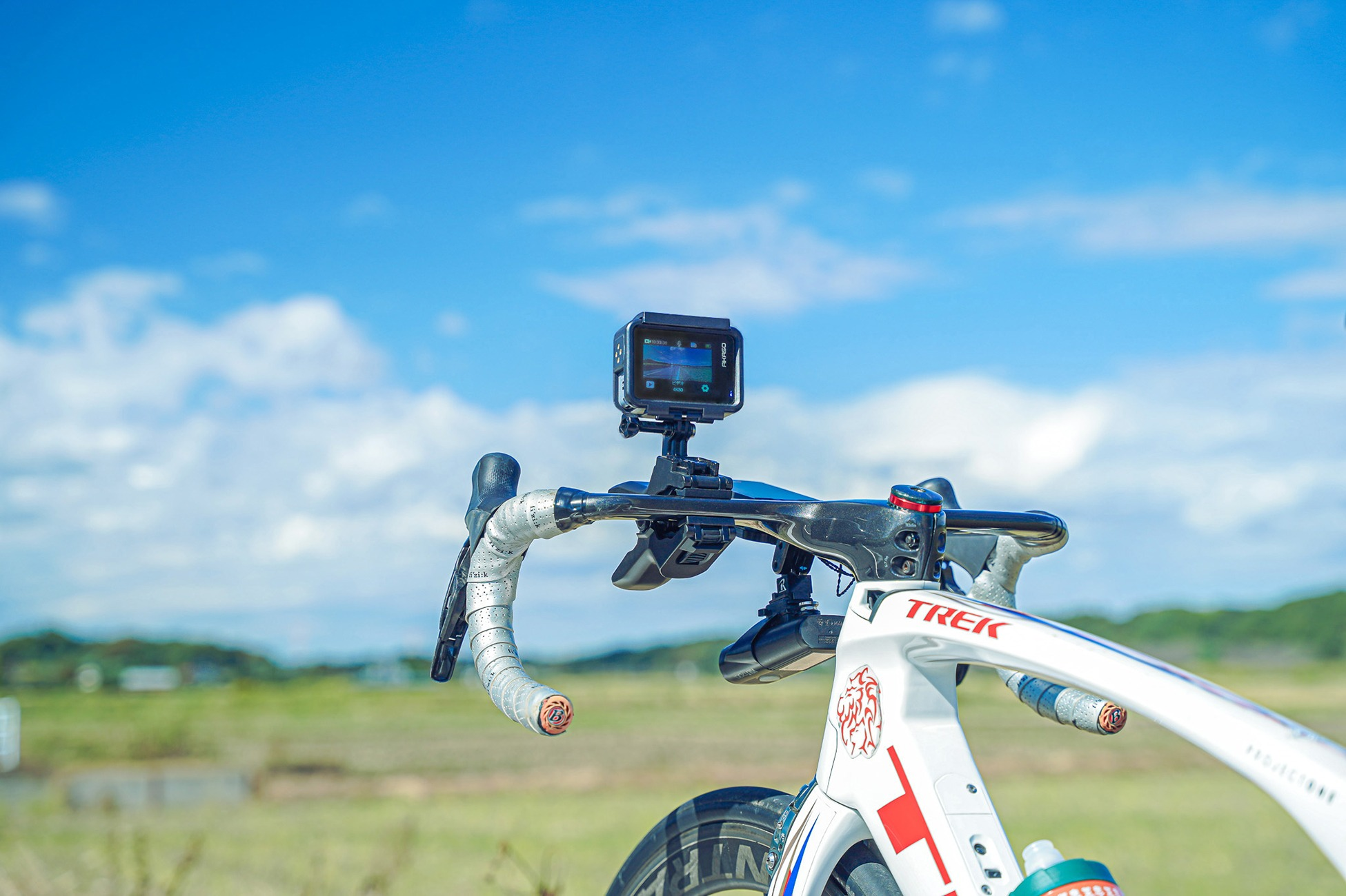 Weiße Rennrad-Lenker mit Action-Kamera und blauem Himmel im Hintergrund.