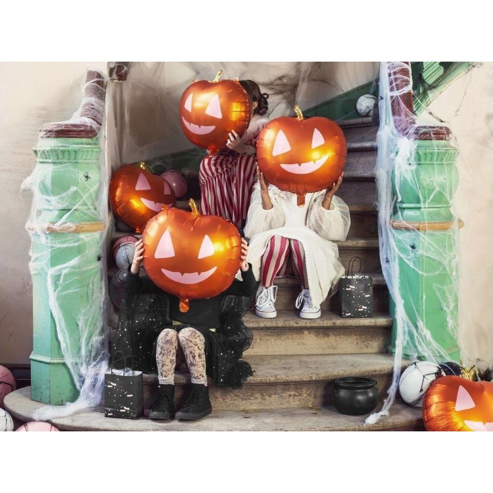 Kinder mit Kürbisballons sitzen auf einer Treppe, dekoriert mit Spinnweben.