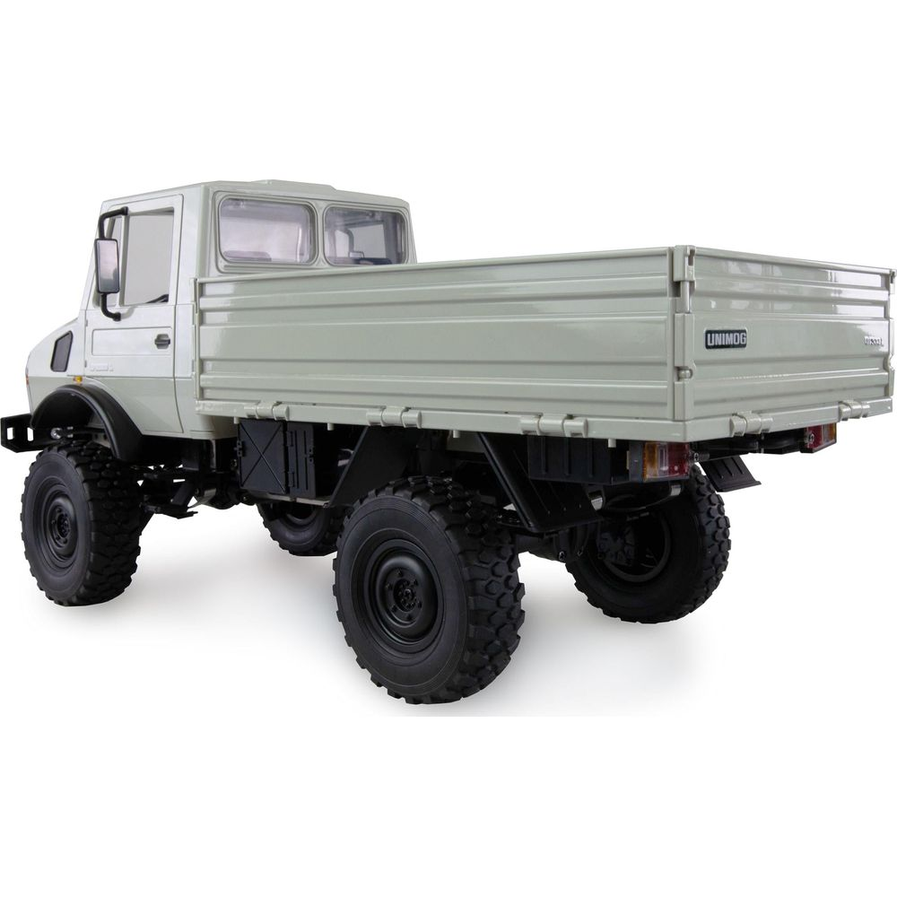 Un camión Unimog gris claro con alta distancia al suelo y plataforma grande.