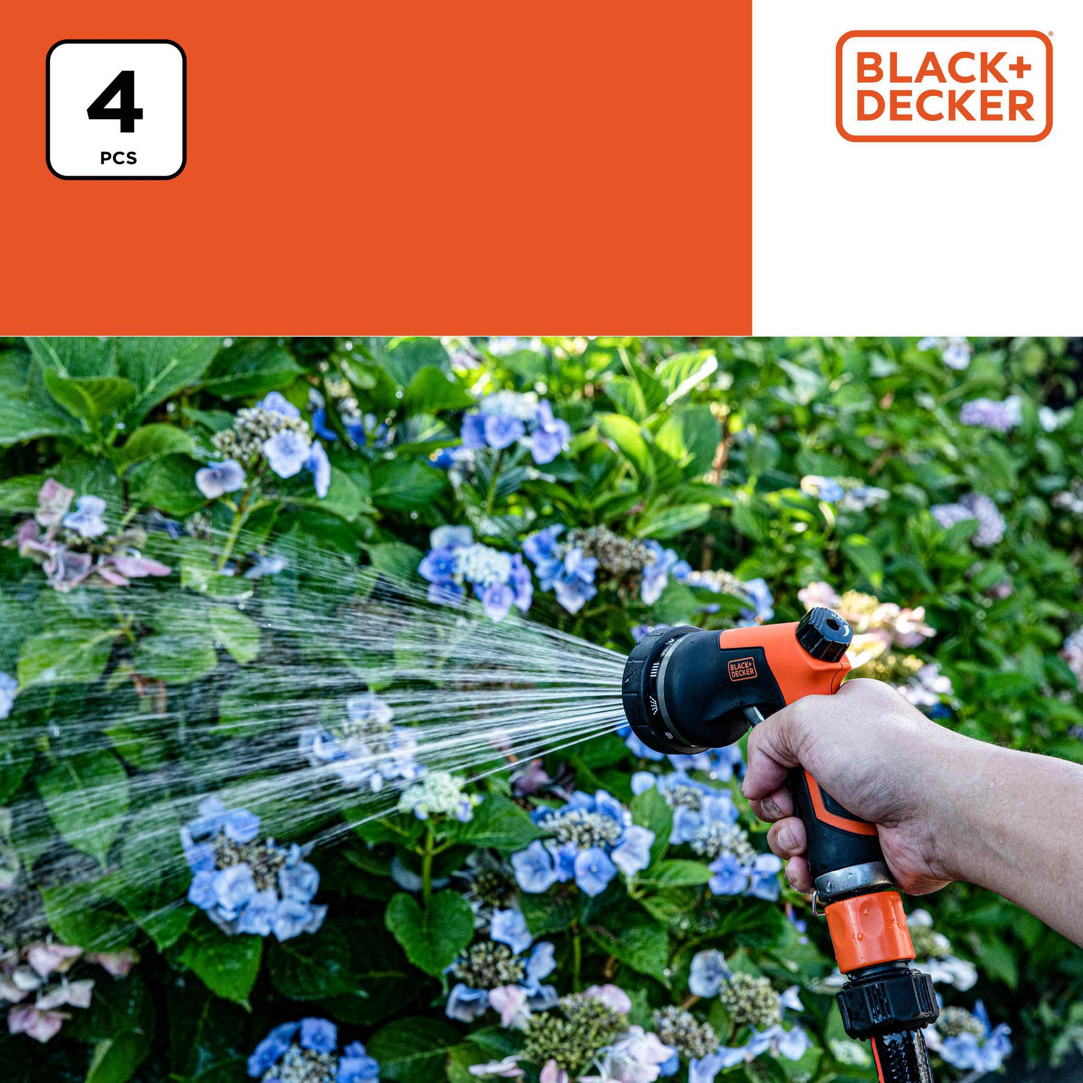 Een hand houdt een slang vast die blauwe en roze hortensia's besproeit.