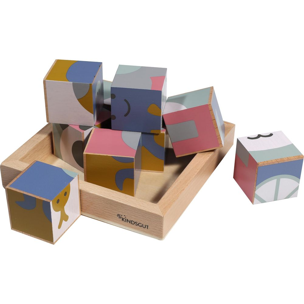 Blocchi di legno con motivi colorati in un vassoio di legno. Un blocco è accanto.